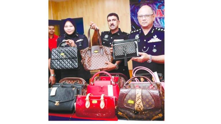 Dang Wangi district police chief ACP Mohd Fahmi Visuvanathan (right) shows branded handbags, on Wednesday, that were seized from a former army personnel who stole 70 handbags worth RM250,000 from an outlet in a shopping complex in Kuala Lumpur. — Bernama