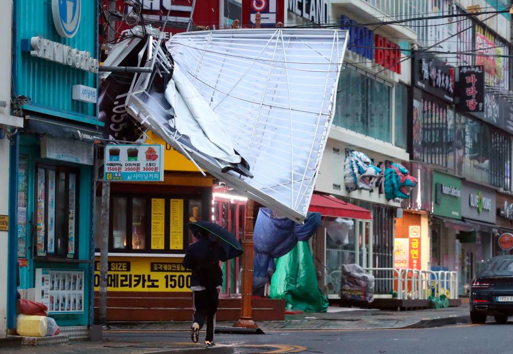 A man walks under the wreckage of a damaged signboard at a shopping street in Changwon on September 6, 2022, as Typhoon Hinnamnor hit South Korea’s southern provinces. AFPPIX