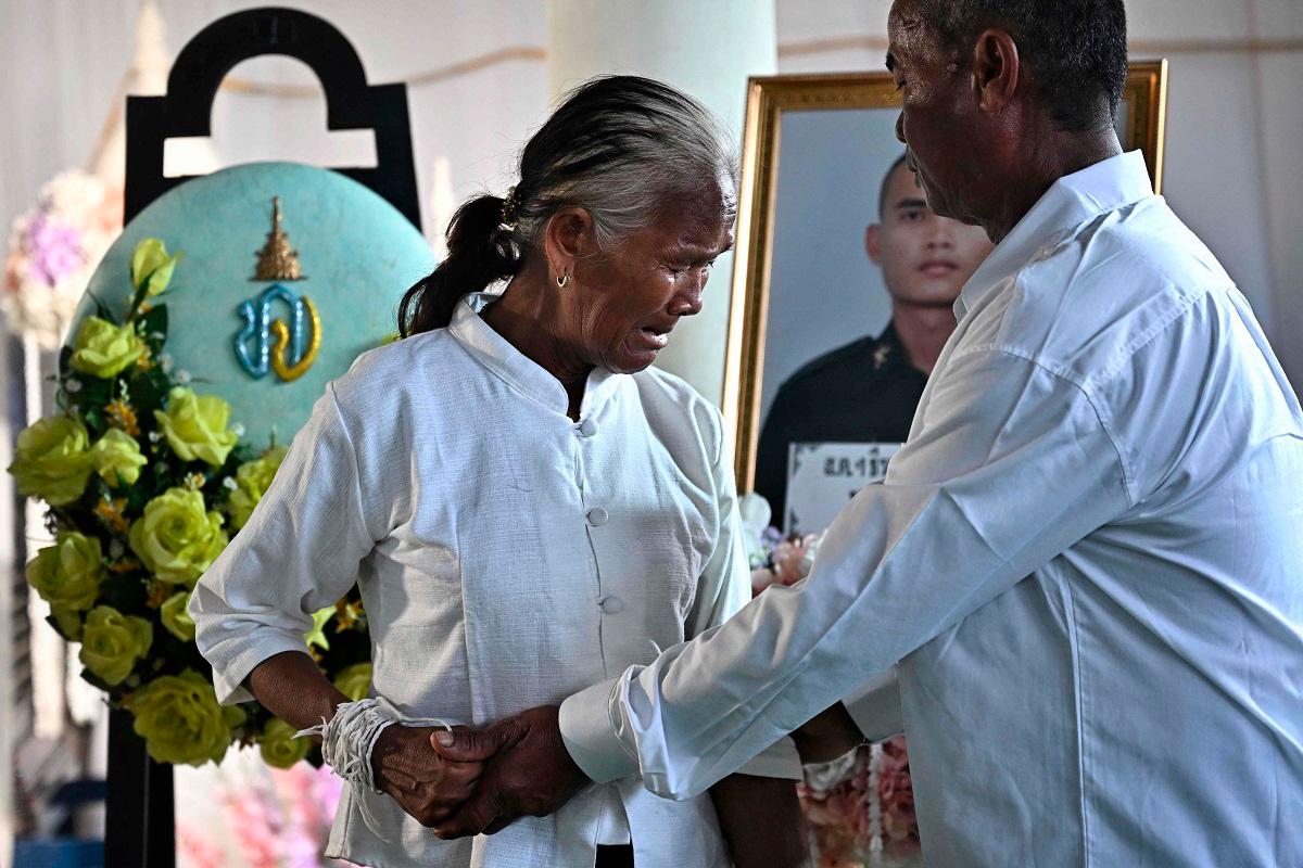 Kimdaeng Krajangthong (R) and Tin Krajangthong (C), the parents of Royal Thai Army soldier Theerayuth Krajangthong, 22, who died in clashes between Thailand and Cambodia in Sisaket province, mourn during funeral rites at a Buddhist temple in the Thai border province of Buriram on July 30, 2025. - Lillian SUWANRUMPHA / AFP