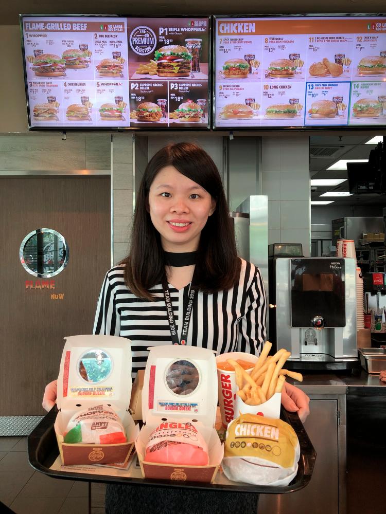 Cosmo Restaurants Sdn Bhd Head of Marketing Goh Yin Yin holding the burgers in special edition boxes. $!Cosmo Restaurants Sdn Bhd Head of Marketing Goh Yin Yin holding the burgers in special edition boxes.