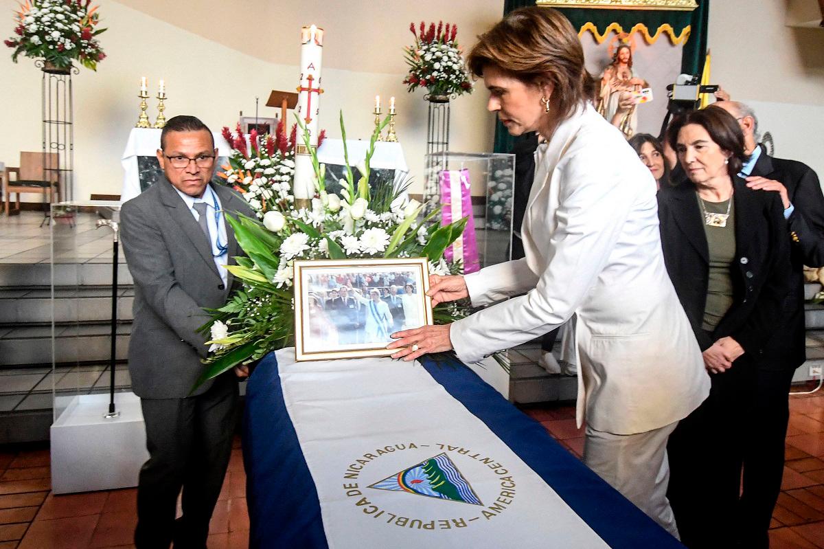 Nicaraguan journalist Cristiana Chamorro (R) arranges a photo on the coffin of her mother, the former Nicaraguan president Violeta Chamorro, during a funeral mass at the Votive Shrine of the Sacred Heart of Jesus in San Jose, Costa Rica on June 16, 2025. - Ezequiel BECERRA / AFP