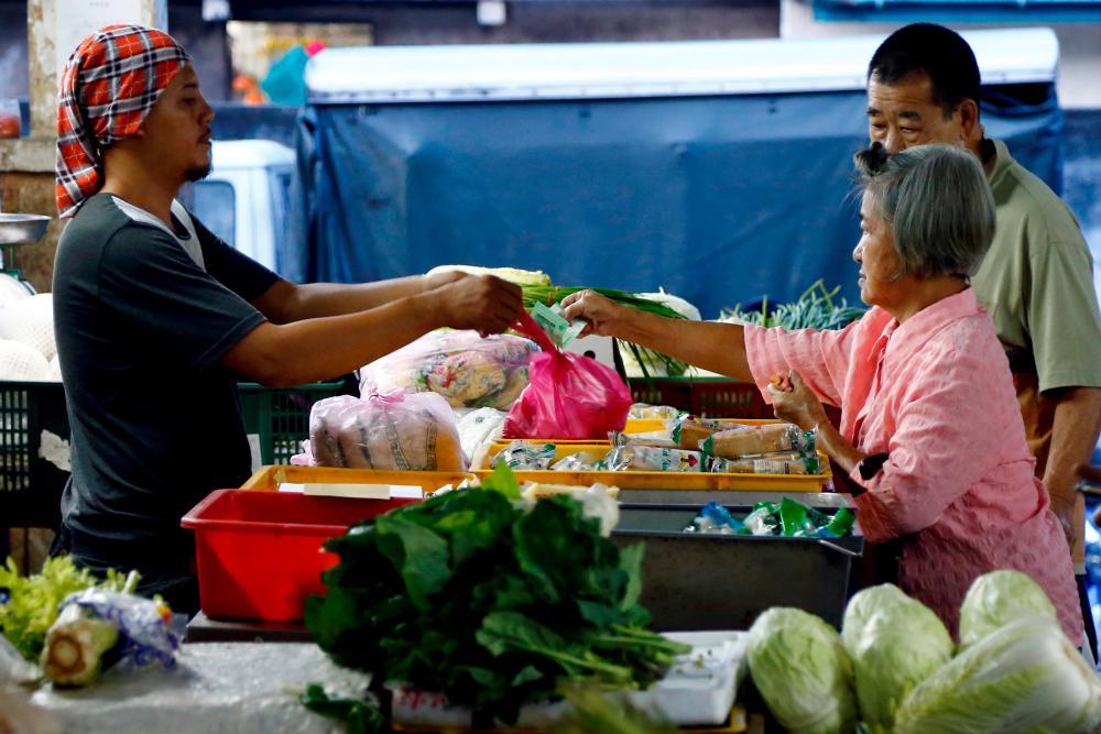 A customer pays for vegetables at a wet market in Klang, outside Kuala Lumpur, Malaysia Oct, 27, 2017. — Reuters