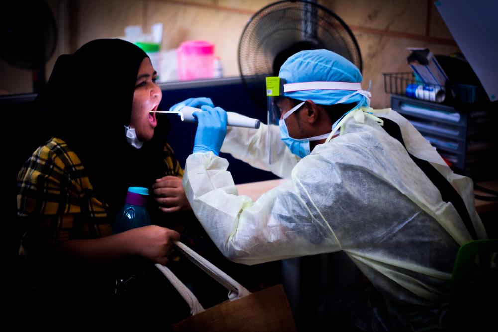 File picture of a doctor at the Thompson Hospital in Kota Damansara collecting the swab of a patient to be tested for Covid-19. — Sunpix by Ashraf Shamsul