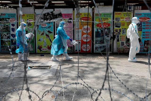 Medical workers wearing protective suits pass by barbed wire at the red zone under enhanced lockdown, amid the coronavirus disease (Covid-19) outbreak, in Petaling Jaya, Malaysia May 11, 2020. — Reuters