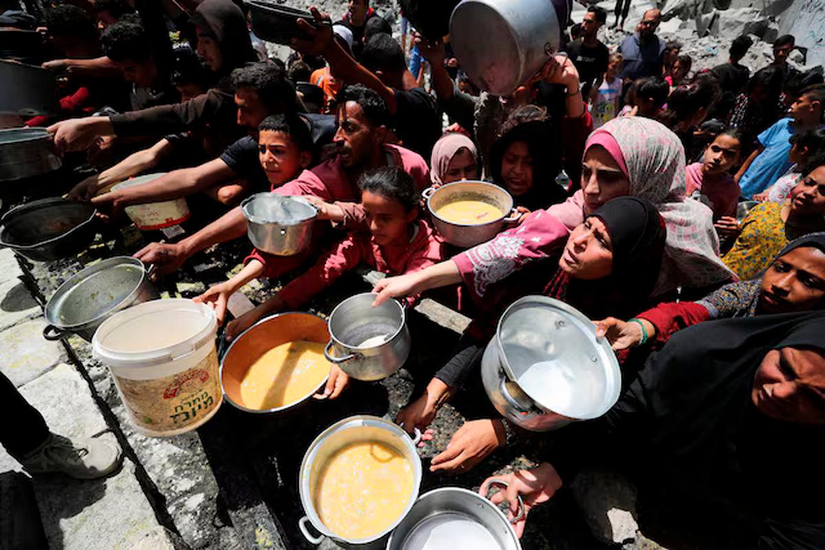 Palestinians wait to receive food cooked by a charity kitchen, in Jabalia, in the northern Gaza Strip, May 19, 2025. REUTERS/Mahmoud Issa/File Photo