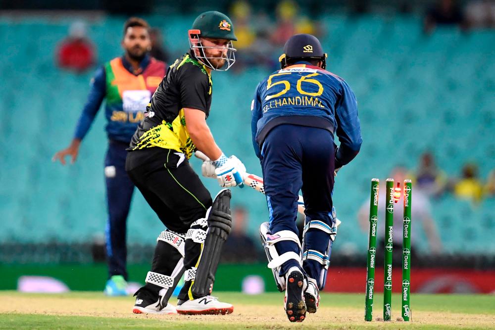 Sri Lankan wicketkeeper Dinesh Chandimal (R) dismisses Australia’s batsman Aaron Finch off Wanindu Hasaranga de Silva during the second T20 international cricket series match between Australia and Sri Lanka at the Sydney Cricket Ground (SCG) on February 13, 2022, in Sydney. AFPPIX