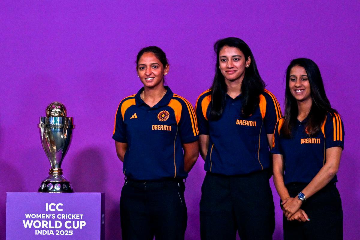Indian team players Jemimah Rodrigues (R), Smriti Mandhana (C) and Harmanpreet Kaur pose with the trophy during an event held to mark 50 days countdown to the 2025 ICC Women’s Cricket World Cup in Mumbai on August 11, 2025. (Photo by Punit PARANJPE / AFP)