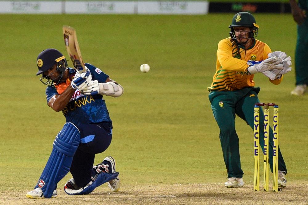 Dasun Shanaka plays a shot as South Africa’s wicketkeeper Quinton de Kock (right) looks on during the first international Twenty20 cricket match at the R Premadasa Stadium in Colombo. – AFPPIX