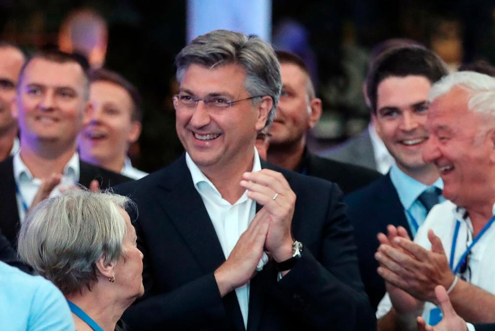 Croatian Prime Minister and leader of the Croatian Democratic Union party (HDZ) Andrej Plenkovic claps as he celebrates with party members after the first results of the parliamentary elections in the garden of the Archaeological Museum in Zagreb, on July 5, 2020. — AFP