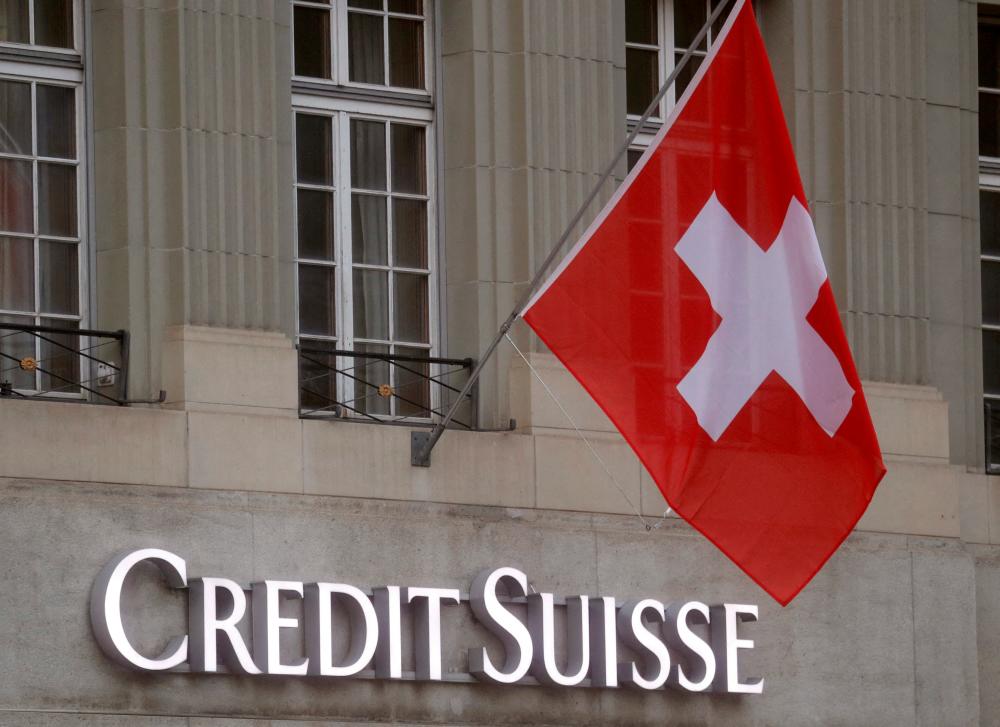 Switzerland’s national flag flies above a logo of Credit Suisse in front of a branch office in Bern. – Reuterspic
