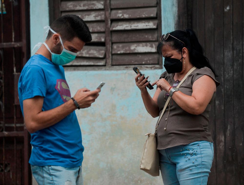 People use their phones in a street of Havana, on July 14, 2021. – AFP