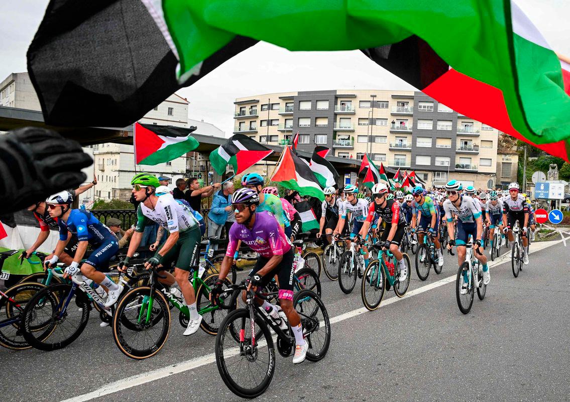 Pro-Palestinian protesters wave flags and shout as the peloton rides by in Poio at the start of the 16th stage of the Vuelta a Espana, a 172 km race between Poio and Castro de Herville, on September 9, 2025. - AFPPIX