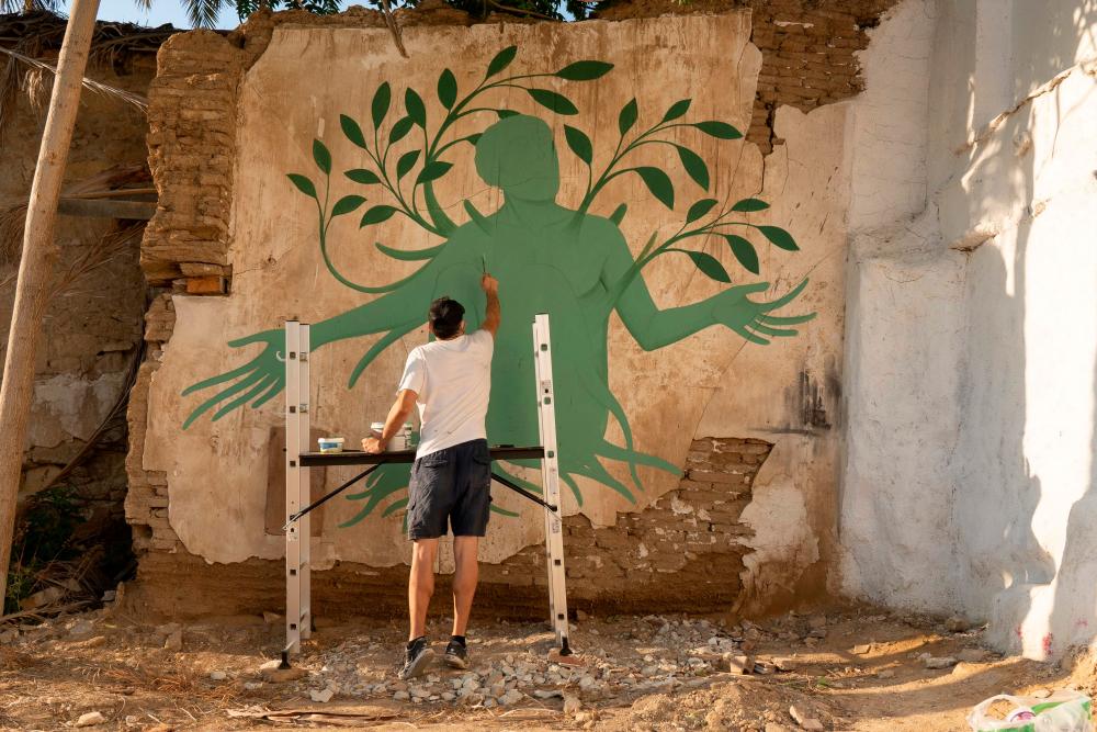 Greek artist Fikos, who describes himself as a neo-muralist, works on one of his murals in the Cypriot capital Nicosia on June 04, 2021. An Athenian neo-muralist is blending Greek mythology and Byzantine iconography with graffiti and street art to depict how the coronavirus has forced people the world over to put down roots. – AFP