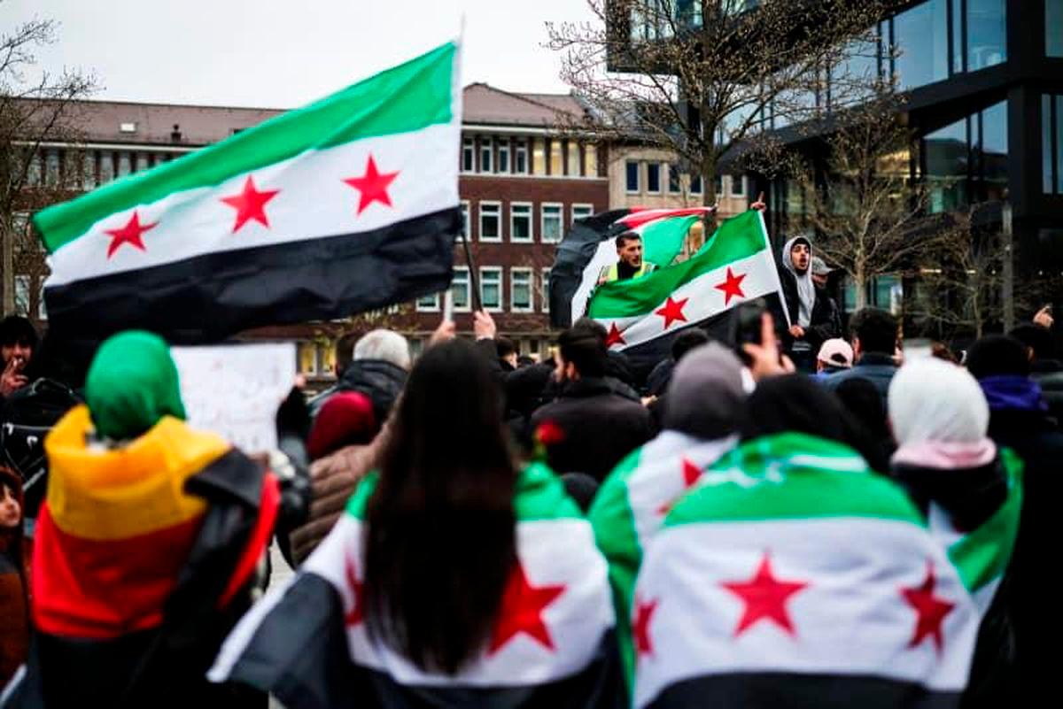 People wrapping themselves in Syrian flags gather in front of Duisburg Central Station. Christoph Reichwein/dpa