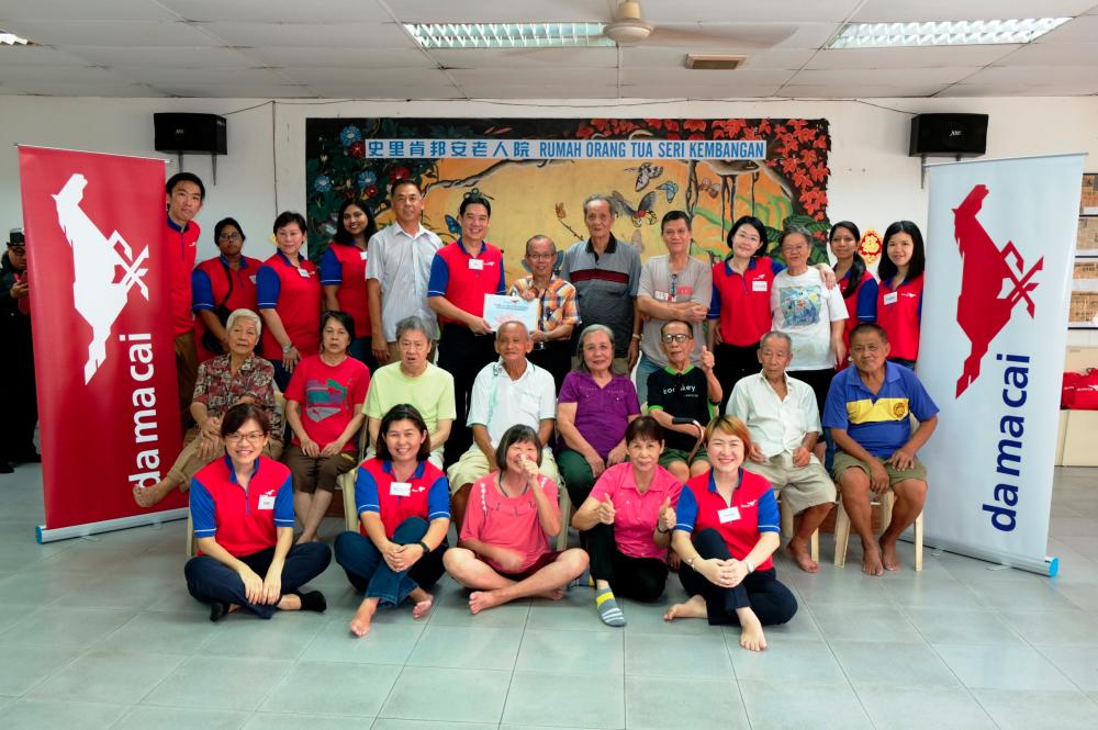 Thong (center, right) receiving the contribution from Da Ma Cai volunteer Yee Kiat Wah.
