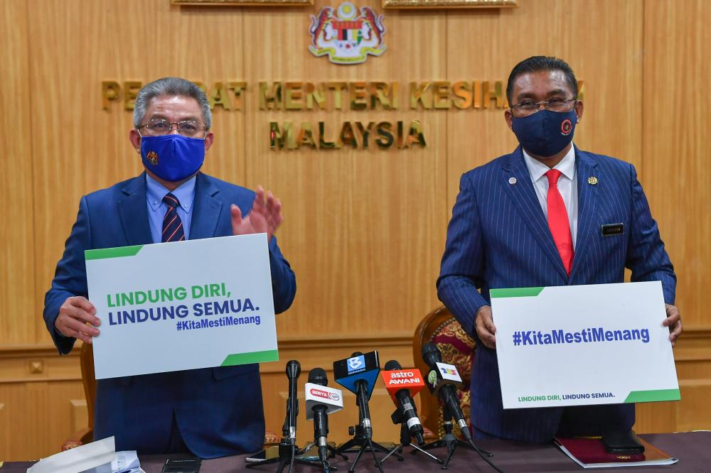 Health Minister Datuk Seri Dr Adham Baba (left) and Minister in the Prime Minister's Department (Parliament and Law) Datuk Seri Takiyuddin Hassan showing the playcard 'Lindungi Diri Lindungi Semua' dan '#KitaMestiMenang' after a press conference at the Health Ministry today. — Bernama