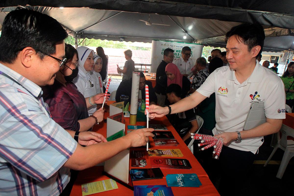 Ben Fong Kok Seng handing over Jalur Gemilang to folks during a recent event. - Pic courtesy of Ben Fong Kok Seng