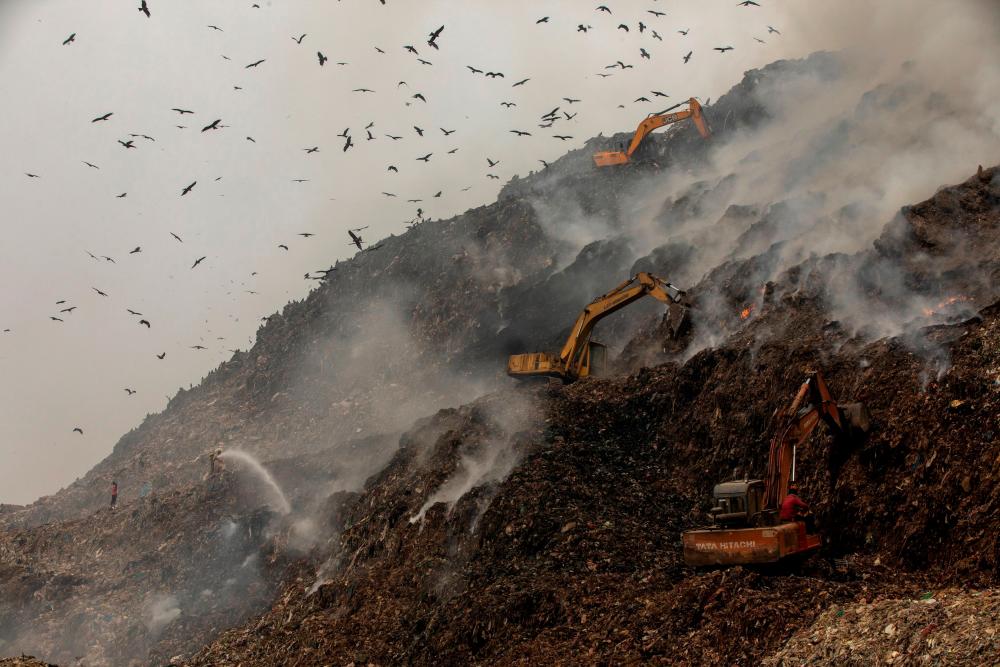 Firefighters and excavators try to douse fire as smoke billows from burning garbage at the Ghazipur landfill site in New Delhi, India, November 25, 2020. — Reuters