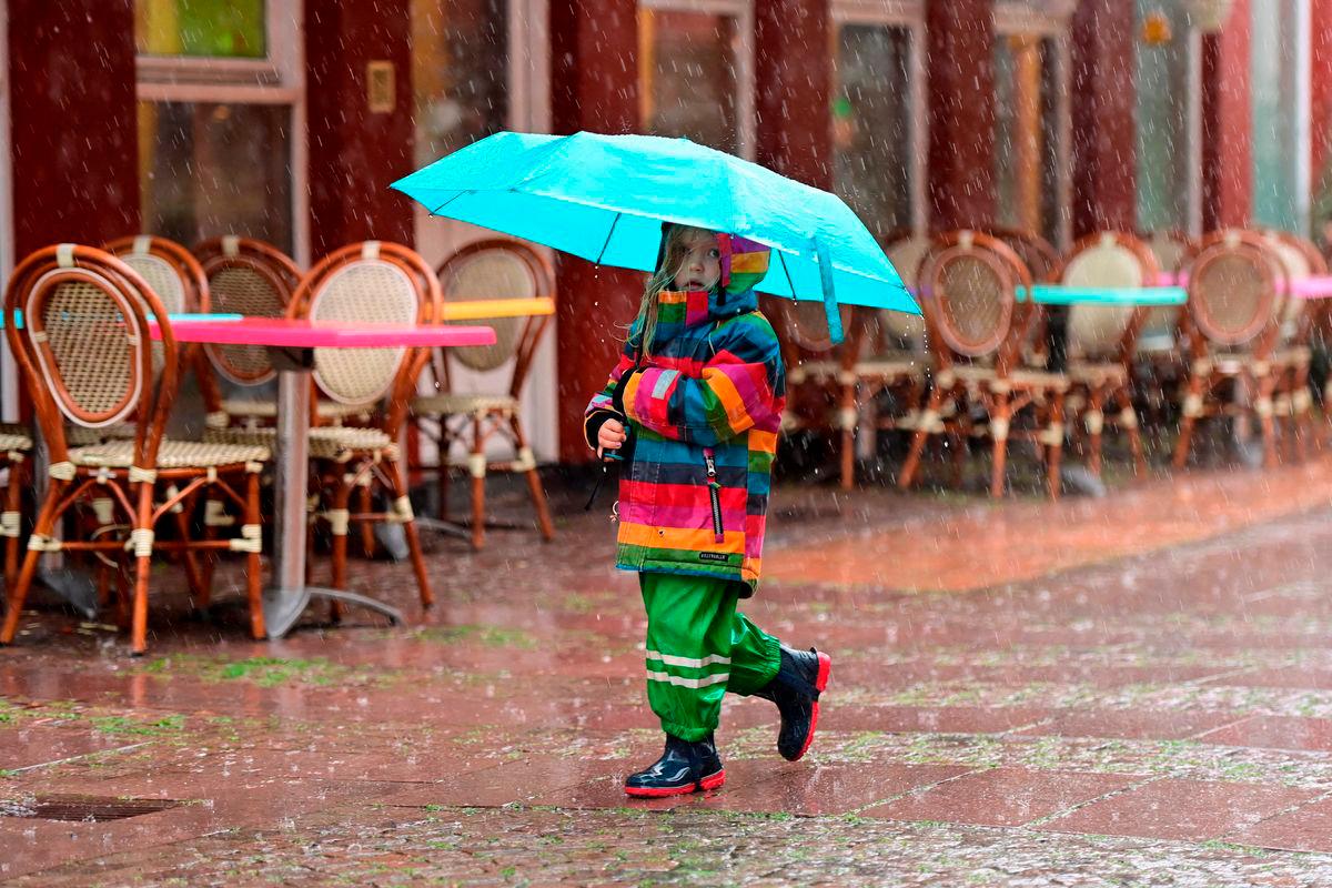 A child walks with an umbrella in the rain in Rudkoebing on Langeland in southern Denmark, on July 22, 2025. (Photo by Thomas Sjoerup / RITZAU SCANPIX / AFP)