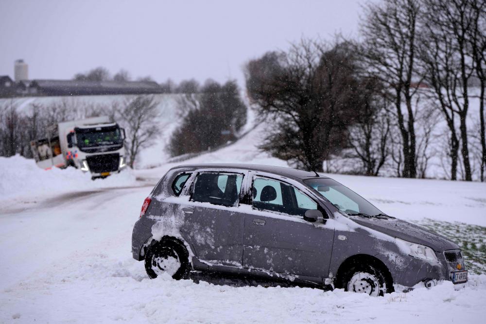 A car and a truck stand off the road as traffic is disturbed because of slippery conditions due to heavy snowfall between OEdum and Mejlby in Jutland, Denmark, on January 4, 2024/AFPPix