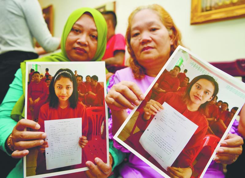 Evelyn Christy Megi (R) and Marsita Mohamad showing pictures of their daughters, who are among the 47 detained in Cambodia. — Bernama