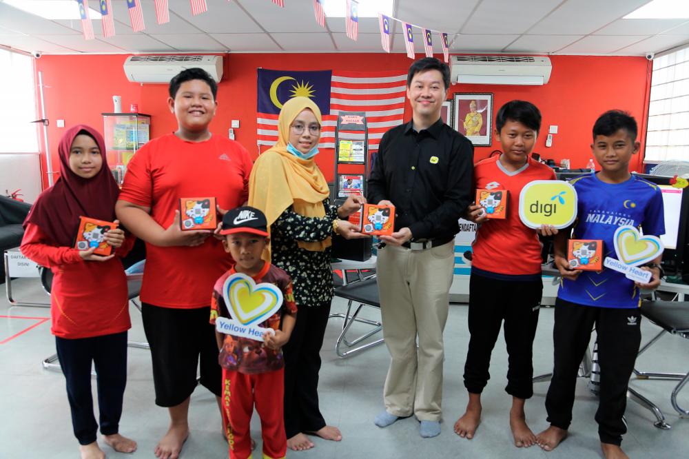 Pusat Internet Kg Hulu Chuchoh manager Mirza Hafuza Mukhtar (centre) and Digi head of sustainability Philip Ling showcasing the micro:bit quick start kit boxes.
