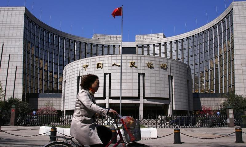 A woman rides past the headquarters of the People’s Bank of China in Beijing, April 3, 2014. REUTERS/Petar Kujundzic
