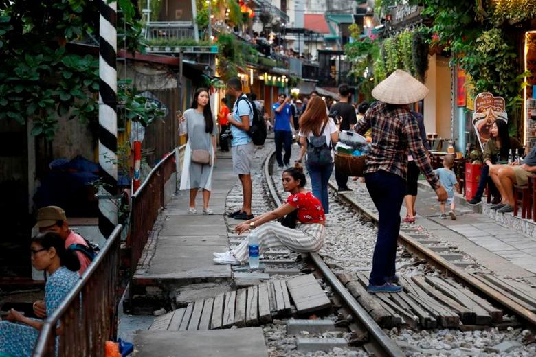 A woman sits on a railway track as tourists gather along it on a street in the Old Quarter of Hanoi, Vietnam October 8, 2019. REUTERSPIX