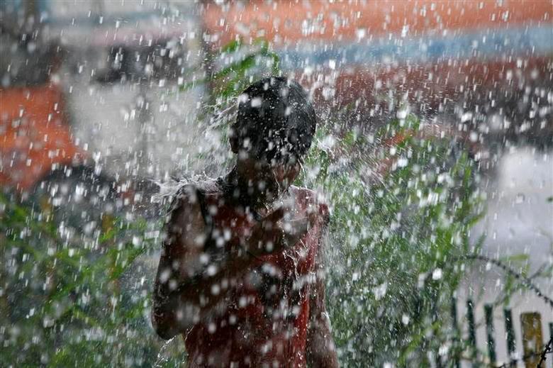 A boy gets himself drenched in rainwater under a flyover during heavy rains. REUTERSPIX