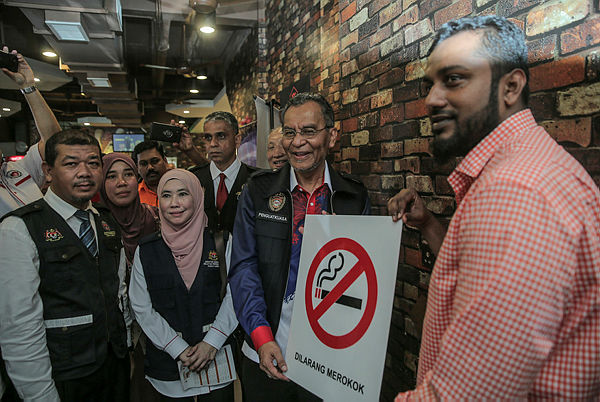 Health Minister Datuk Seri Dr Dzulkefly Ahmad hands over a no smoking sign to food shop owner Muhammad Riyasutin (R) as part of the beginning of the smoking ban on Jan 1, 2019. — Bernama