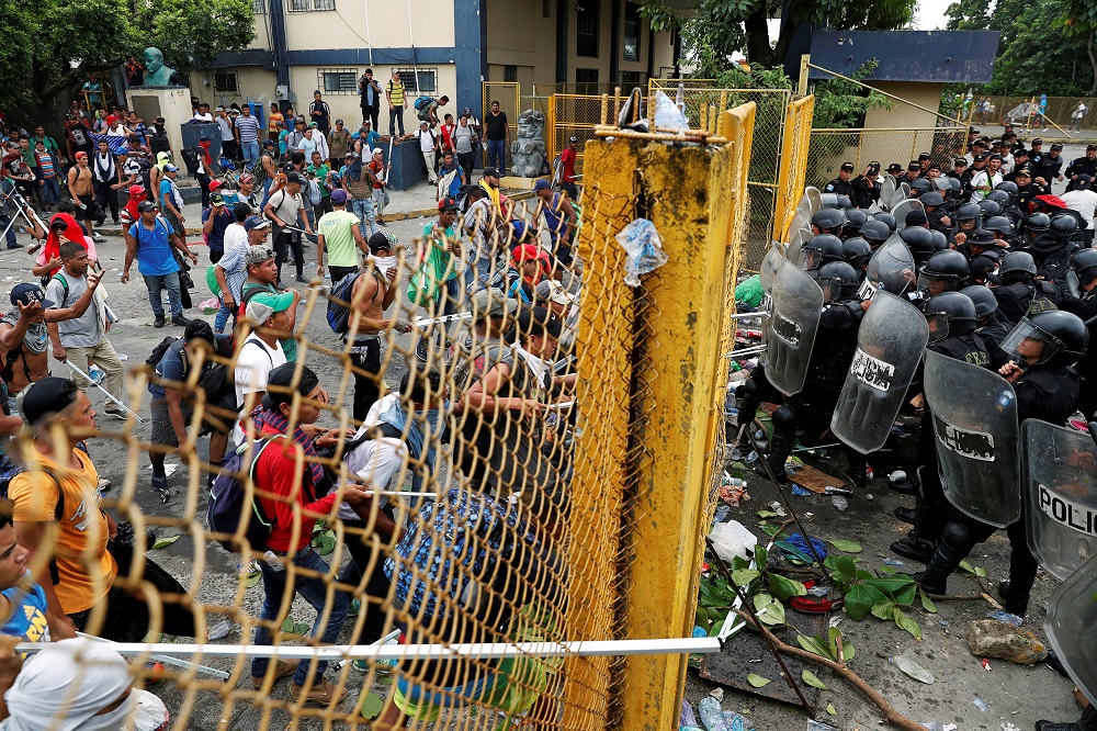 Men, part of a caravan of thousands of migrants from Central America en route to the US, push the border gate as they try to cross into Mexico and carry on their journey, in Tecun Uman, Guatemala, Oct 28, 2018. — Reuters