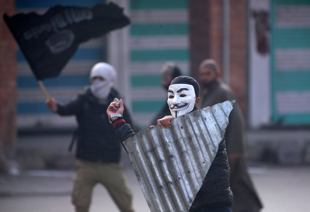 A demonstrator wearing a Guy Fawkes mask throws a stone towards the Indian police during a protest after Friday prayers, in Srinagar Dec 14, 2018. — Reuters