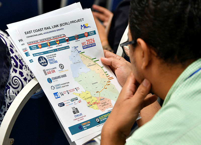A reporter looks at a briefing on the renegotiated deal for the ECRL project, during Prime Minister Tun Dr Mahathir Mohamad’s press conference, in Putrajaya, on April 15, 2019. — Bernama