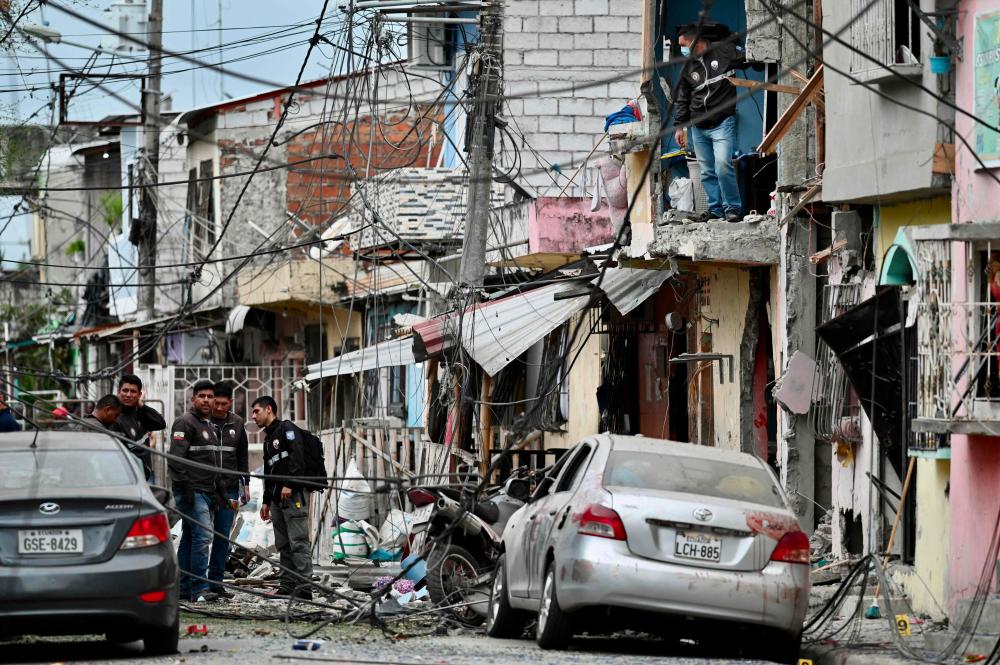 Members of the National Police inspect the site of an explosion, which the Ecuadorean government attributes to organized crime, in southern Guayaquil, Ecuador, on August 14, 2022. - AFPPIX
