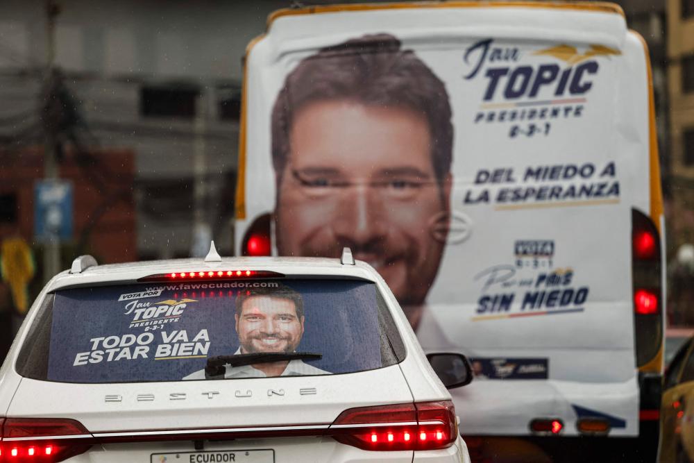 A car and a bus with political advertisements of presidential candidate Jan Topic are seen in Quito on August 15, 2023. Next Sunday August 20, presidential elections will be held in Ecuador. AFPPIX