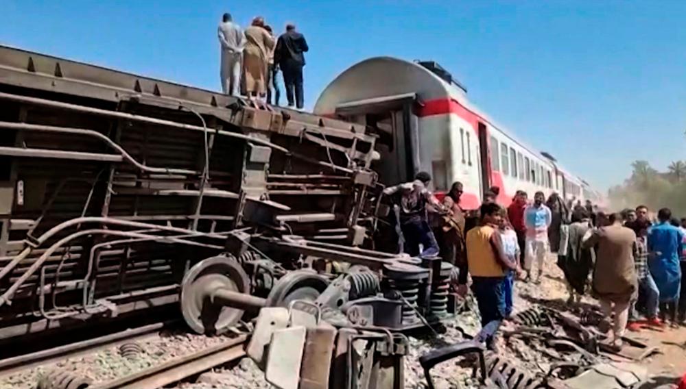 This screengrab provided by AFPTV ahows people gathered around the wreckage of two trains that collided in the Tahta district of Sohag province, some 460 kms (285 miles) south of the Egyptian capital Cairo, reportedly killing at least 32 people and injuring scores of others, on March 26, 2021. - AFP