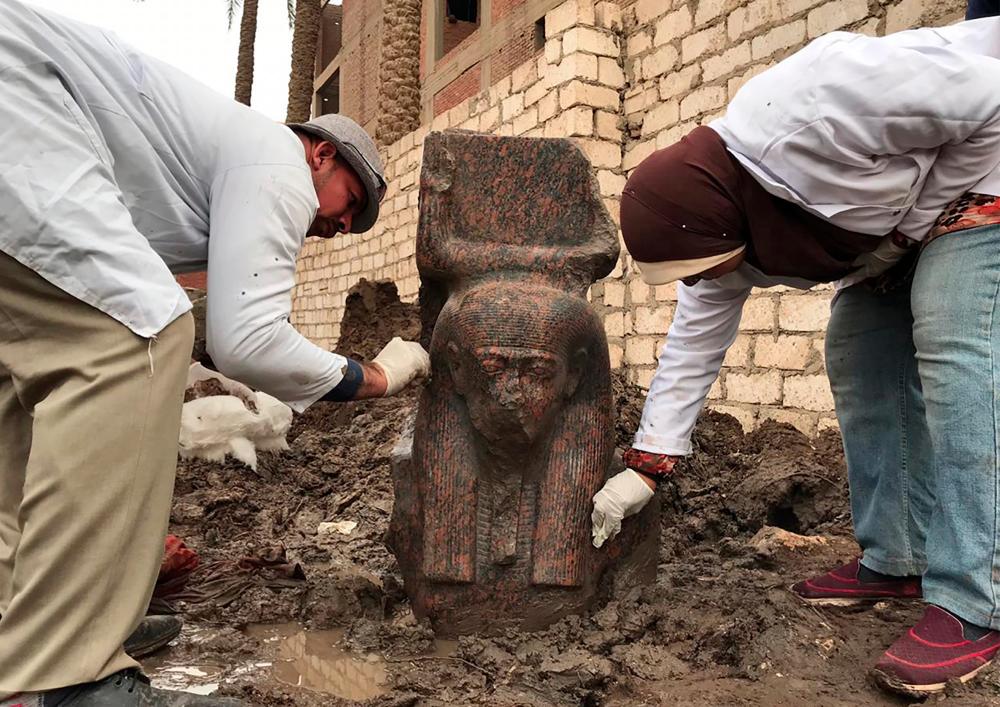 A handout picture released by the Egyptian Ministry of Antiquities on Dec 11, shows archaeologists cleaning a newly-discovered fragment of a statue of ancient Egyptian Pharaoh Ramesses II, found at a private plot of land in the village of Mit Rahinah, near the historical site of Memphis and the Saqqara necropolis, south of the Egyptian capital Cairo. — AFP