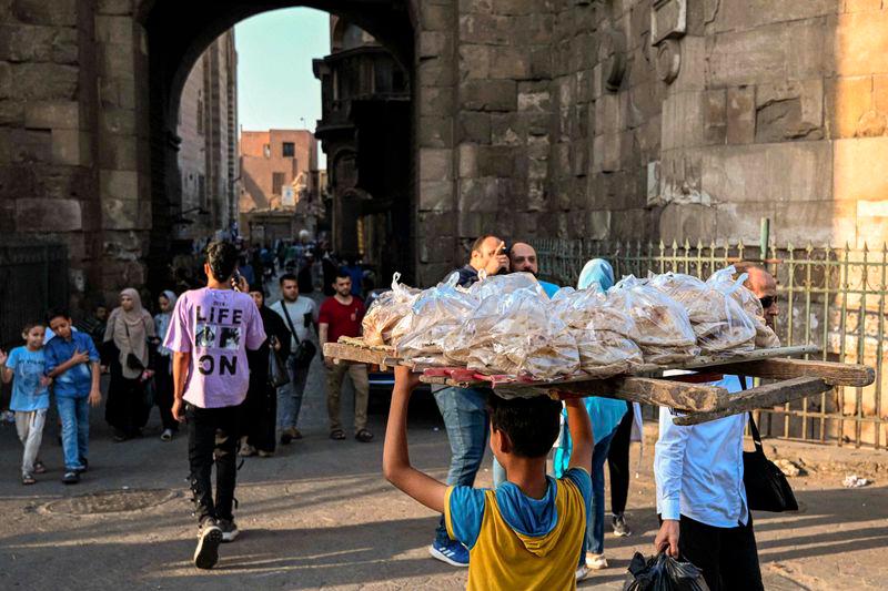 A young boy delivers freshly-baked bread in the al-Darb al-Ahmar district in the old quarters of Cairo on May 28, 2024. - AFPPIX