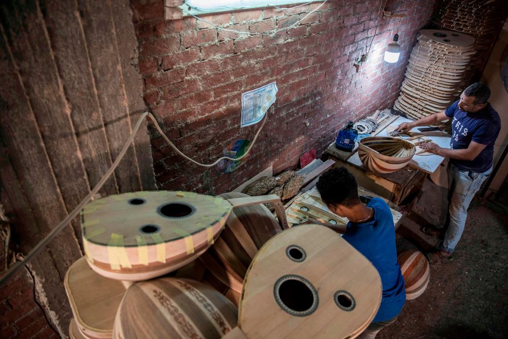 Men work on Arabian Ouds at a workshop belonging to Khaled Azzouz, a veteran oud-maker at the al-Marg district on the outskirts of the Egyptian capital Cairo on October 26, 2020. The oud, a centuries-old stringed instrument popular in the Middle East, is a key element of classical Arabic music. Azzouz said he had observed “unprecedented interest” in the out during the global health pandemic. / AFP / Khaled DESOUKI