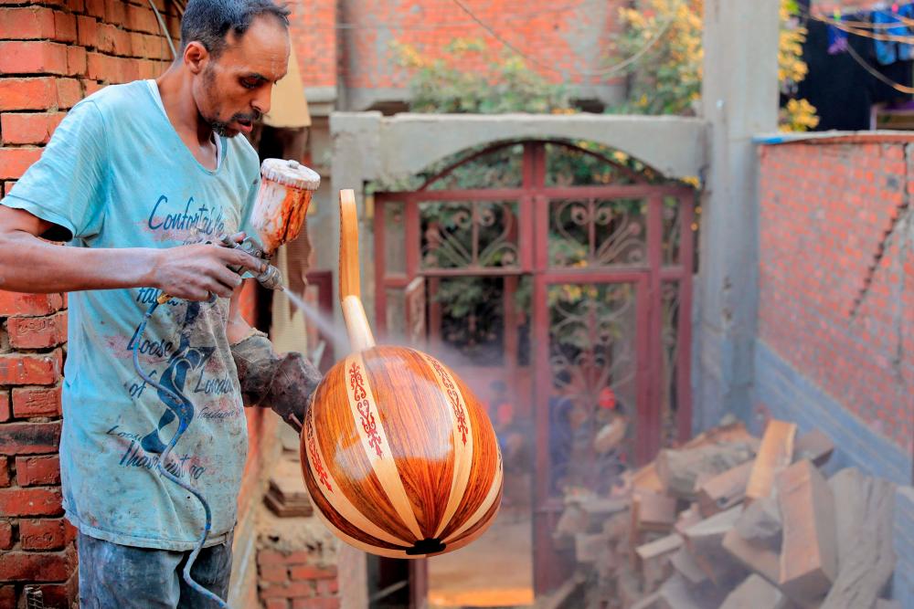 $!A man sprays varnish on an Arabian Oud at a workshop belonging to Khaled Azzouz, a veteran oud-maker at the al-Marg district on the outskirts of the Egyptian capital Cairo on October 26, 2020. The oud, a centuries-old stringed instrument popular in the Middle East, is a key element of classical Arabic music. Azzouz said he had observed “unprecedented interest” in the out during the global health pandemic. / AFP / Khaled DESOUKI
