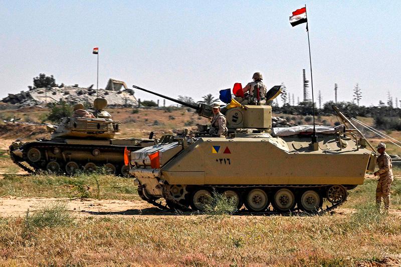 An Egyptian army M60 main battle tank and an infantry fighting vehicle (IFV) are deployed near the Egyptian side of the Rafah border crossing with the Gaza Strip on March 23, 2024, amid the ongoing conflict in the Palestinian territory between Israel and the Palestinian militant group Hamas. (Photo by Khaled DESOUKI / AFP)