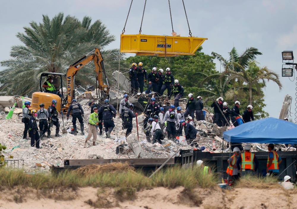 After a brief stoppage to demolish the standing remains, Search and Rescue personnel continue working in the rubble pile of the partially collapsed 12-story Champlain Towers South condo on July 5, 2021 in Surfside, Florida. The decision by officials to bring the rest of the building down was brought on by the approach of Tropical Storm Elsa and fears that the structure might come down in an uncontrolled fashion. Over one hundred people are missing as the search-and-rescue effort continues. -AFP