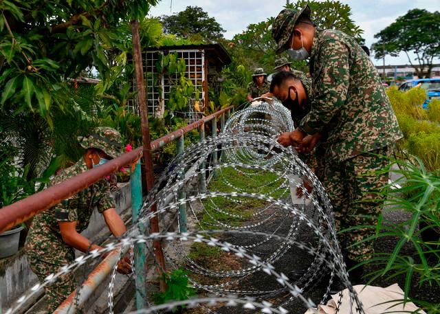 The Armed Forces personnel installing barbed wires around the housing area yesterday afternoon.-Bernama