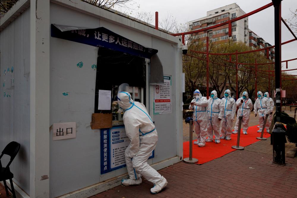 Epidemic-prevention workers line up to get swab tested on Monday. Chinese health officials say the country plans to speed up Covid-19 vaccinations for elderly people. – Reuterspic