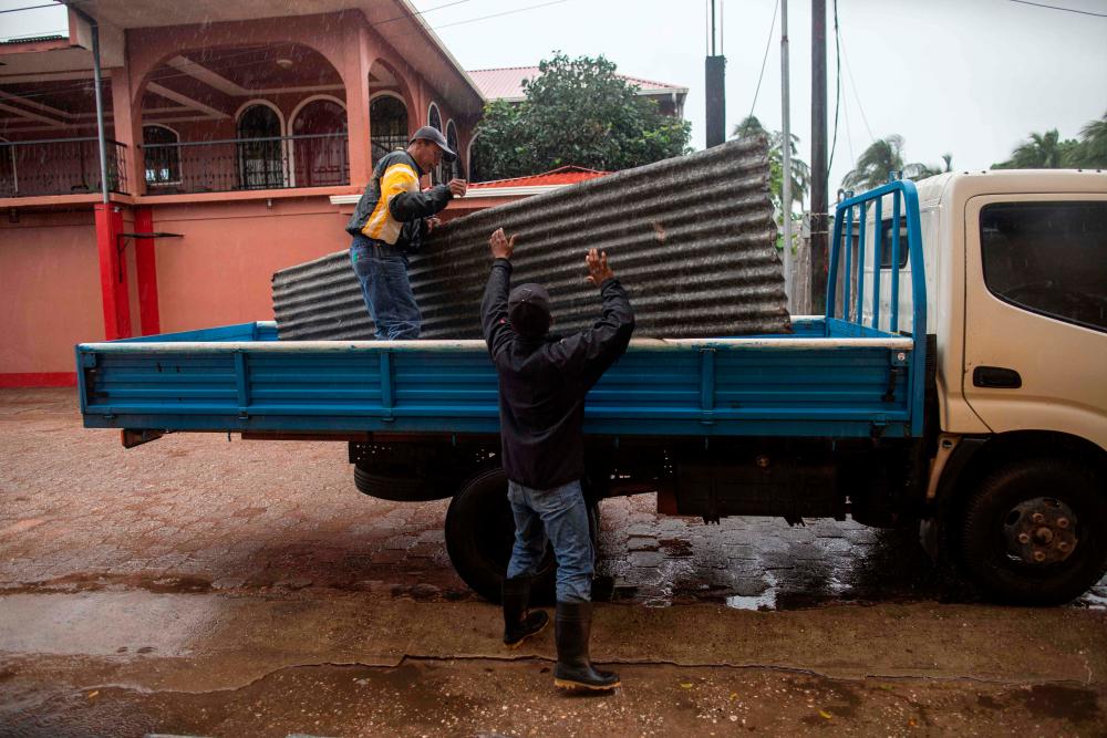 Workers carry zinc sheets to protect windows before the arrival of Hurricane Eta, in Bilwi, Puerto Cabezas, Nicaragua, on November 2, 2020. — AFP