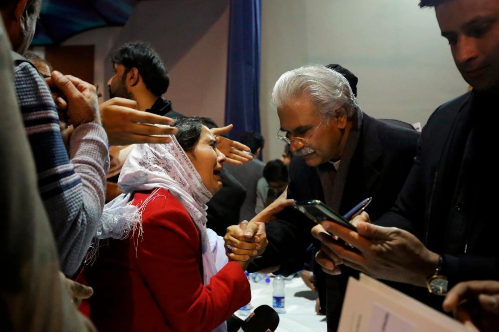 Pakistan's Health Minister, Zafar Mirza (R), interacts with the mother of a Pakistani student, who is stuck in the locked down Hubei province at the center of China's coronavirus outbreak, as people demand evacuation of their children during a meeting in Islamabad, Pakistan February 19, 2020. - Reuters