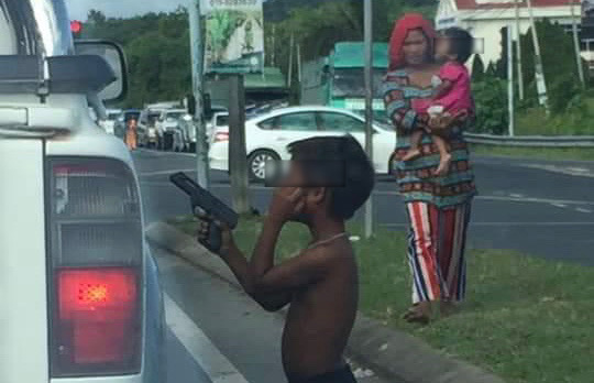 The boy with a toy gun while begging at Bandar Sri Perdana traffic light. - TheBorneoPost