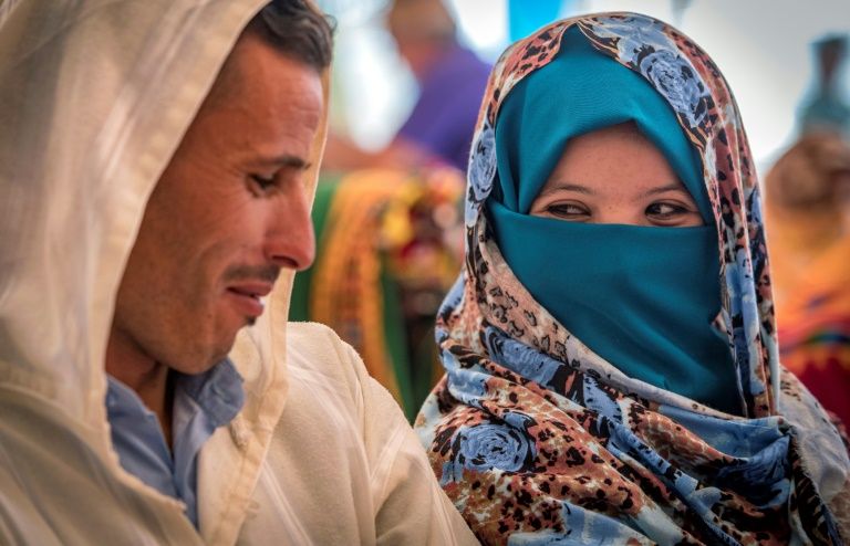 A young Amazigh couple smile at each other as they wait for their turn at a group wedding in Morocco’s Atlas mountains. — AFP