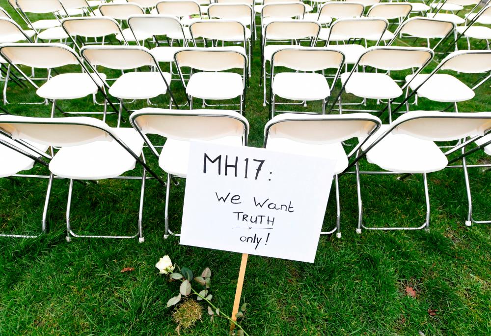 A protest sign stands in front of a row of chairs as family members of victims of the MH17 crash lined up empty chairs for each seat on the plane during a protest outside the Russian Embassy in The Hague, Netherlands March 8, 2020. - Reuters