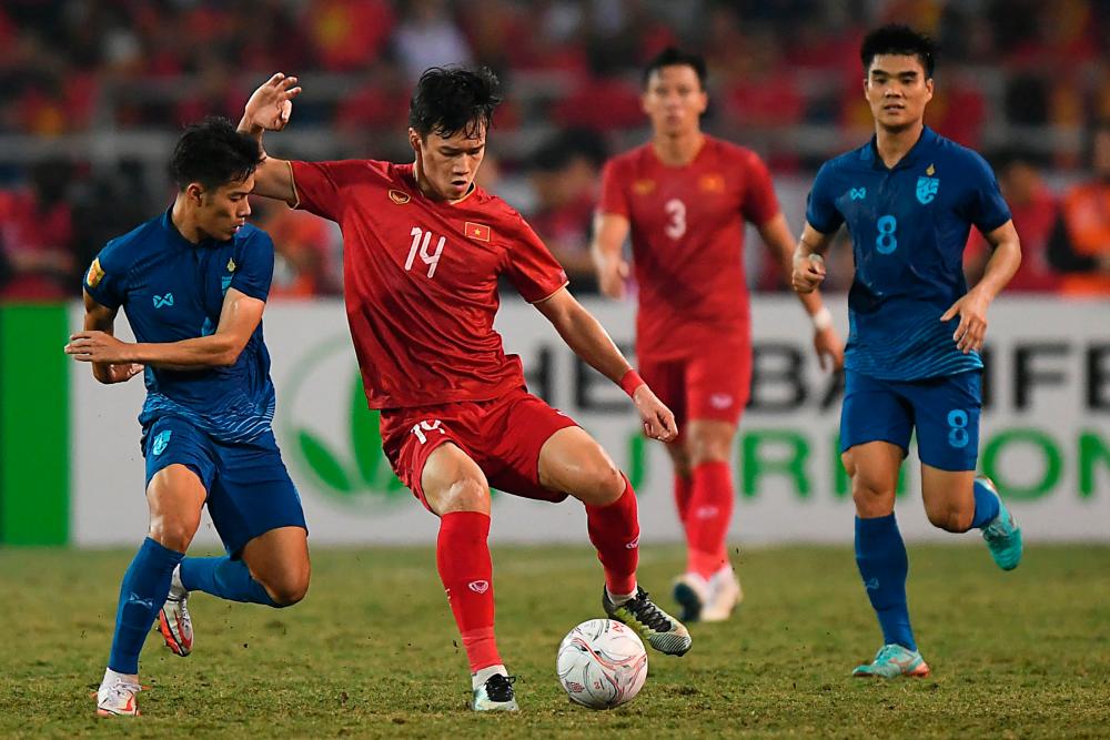 Vietnam's Nguyen Hoang Duc (C) controls the ball past Thailand's Sarach Yooyen (L) during the first leg of the AFF Mitsubishi Electric Cup final football match between Vietnam and Thailand at My Dinh National Stadium in Hanoi on January 13, 2023/AFPPIX